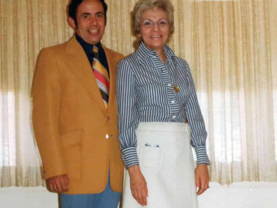 Man in beige jacket and bright toe next to smiling woman in silver dyed hair