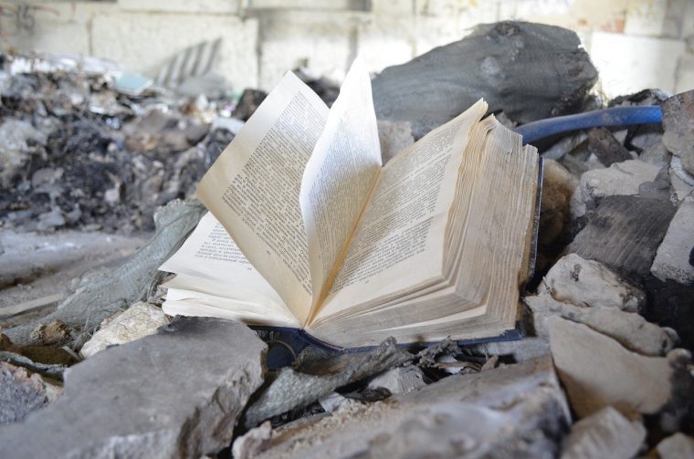 Open tattered book sitting atop of pile of rubble