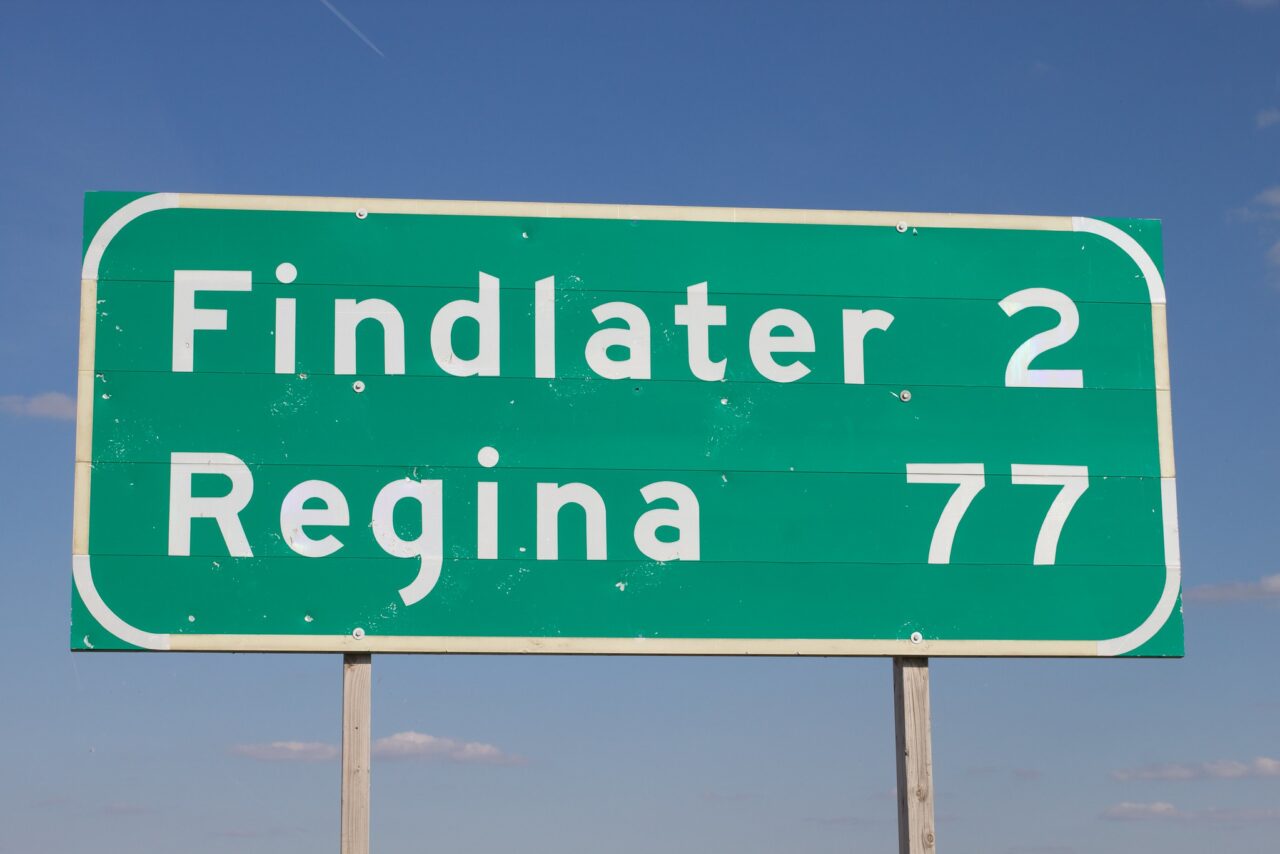 A highway sign listing Findlater (2) above Regina (77) - yes real town names in Saskatchewan!