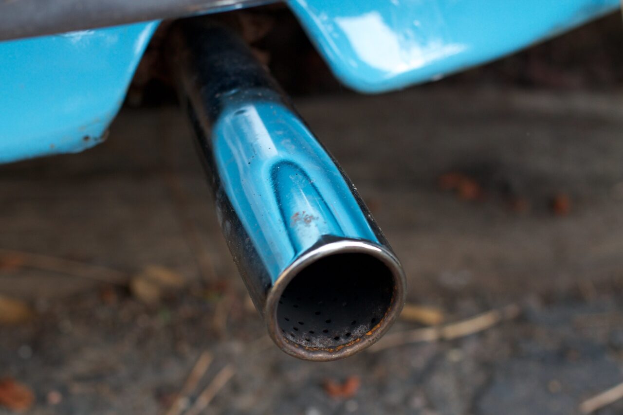 Closeup of a shiny exhaust pipe emerging from the bumper of a bright blue Volkswagen Beetle (well you cannot see what kind of car it is but I was there).