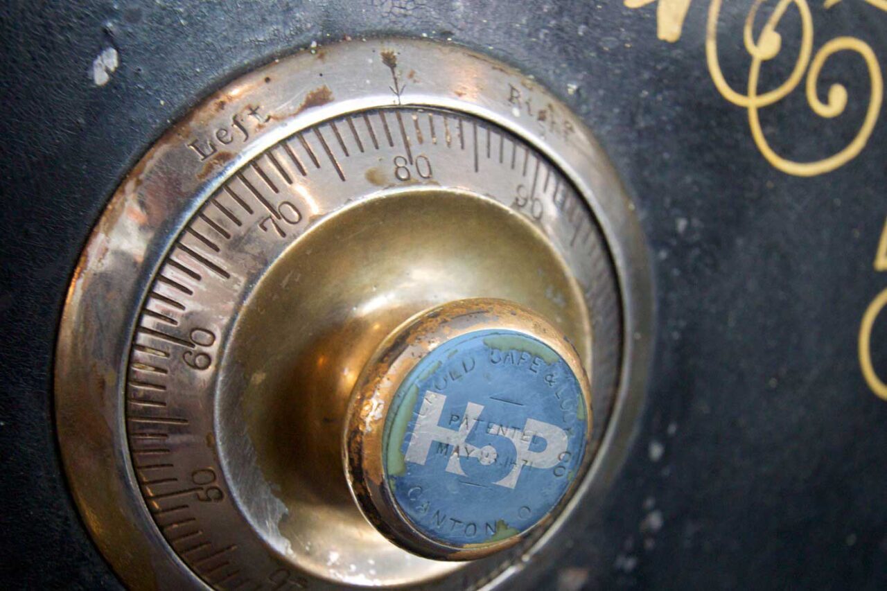 A numbered dial on the front of an old style metal bank safe, with an H5P logo superimposed on the knob