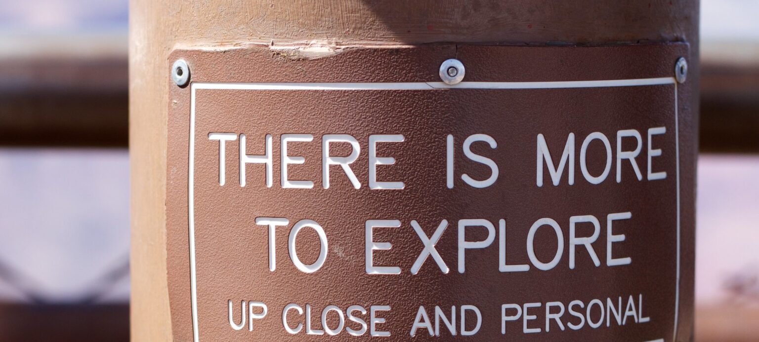 A brown metal post with words "There is more to explore, up close and personal"