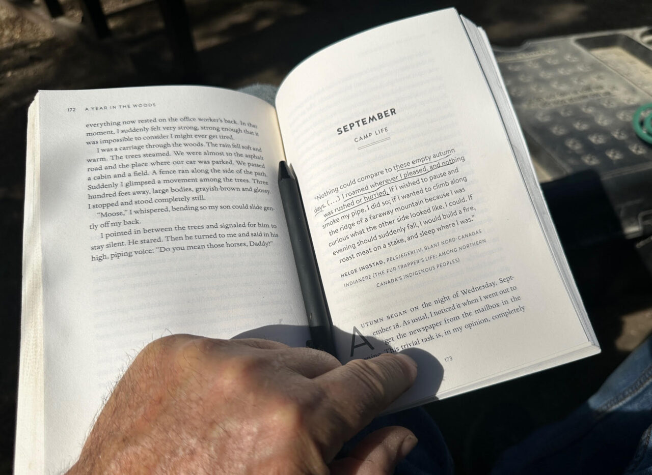 Open book to a chapter in a book titles "September--Camp Life".  A hand, mine, holds the page open, a pen sits in the spine, and a section of the opening quote is underlined, "these empty autimn days.... I roamed where I pleased, noting was rushed or hurried"