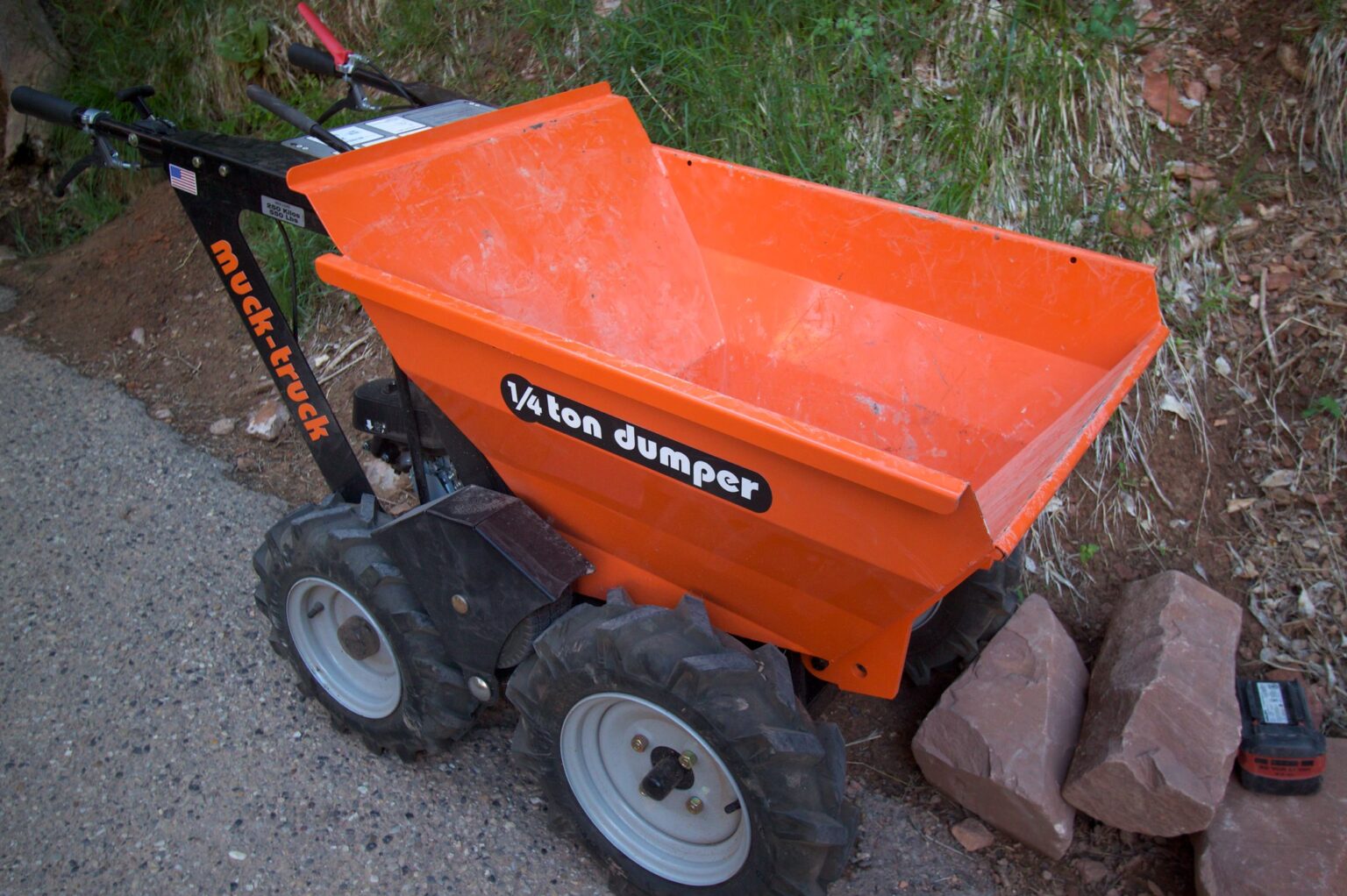 An orange cart for carring rocks and dirt with big knobby wheels. It's label is "muck-truck"