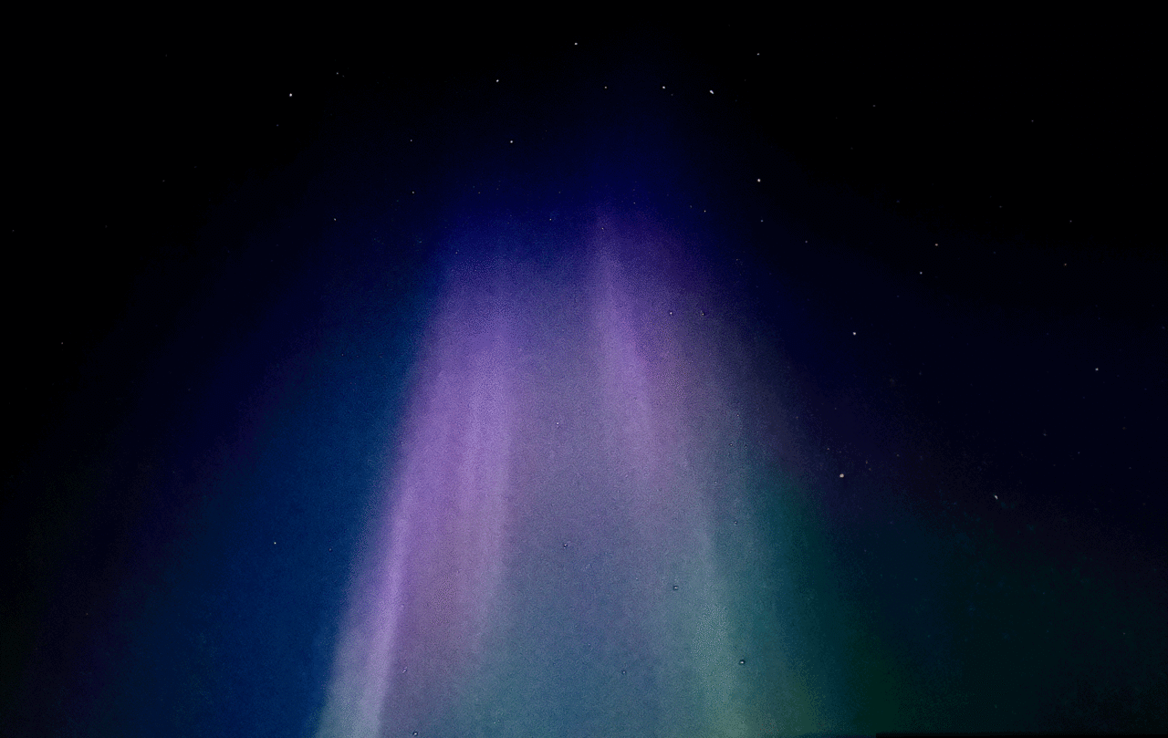 Aurora borealis with purple, blue, and green lights against a starry night sky, below Ursa Major.