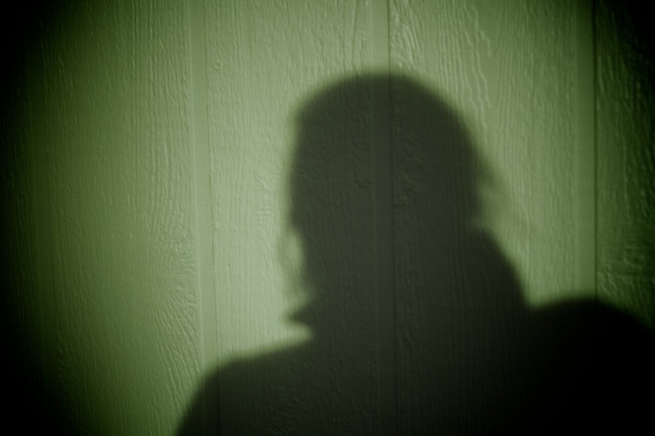 Shadow of a person, mysterious, against a spotlight on a wall.