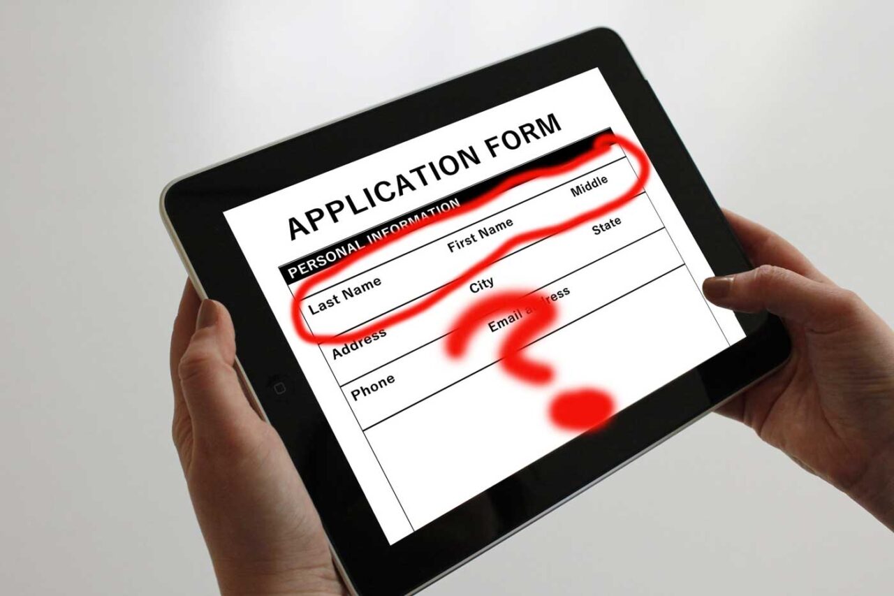 Hands holiding a tablet device, on screen is a label Application form with fields for first, middle, last names- these are circled with a thick red line and a question mark below.