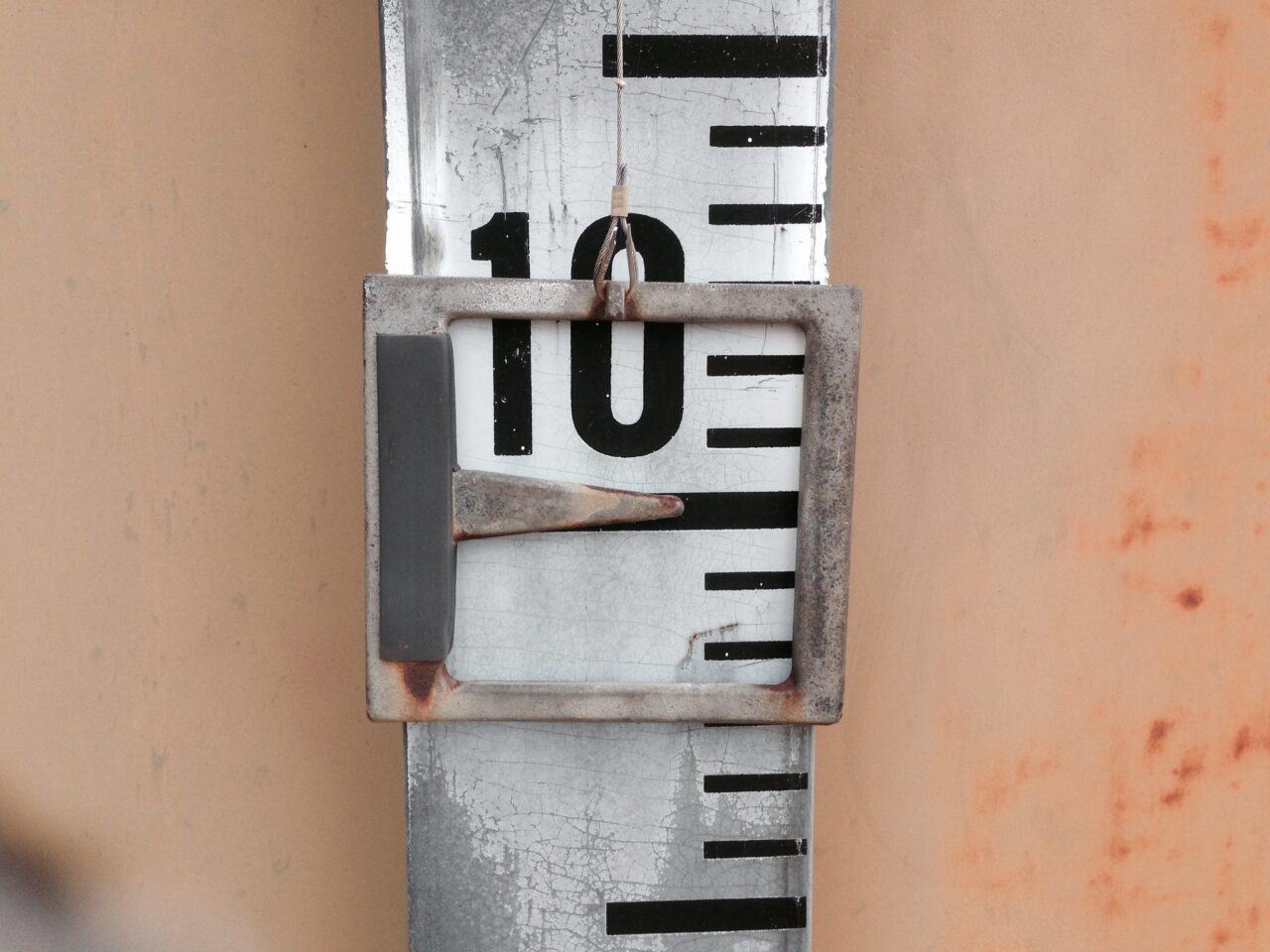 A vertical scaled reading for levels in a water tank, the pointer exactly at the value 10.