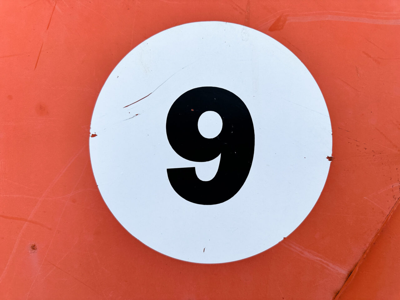 Large number 9 in a white circle against an orange background.