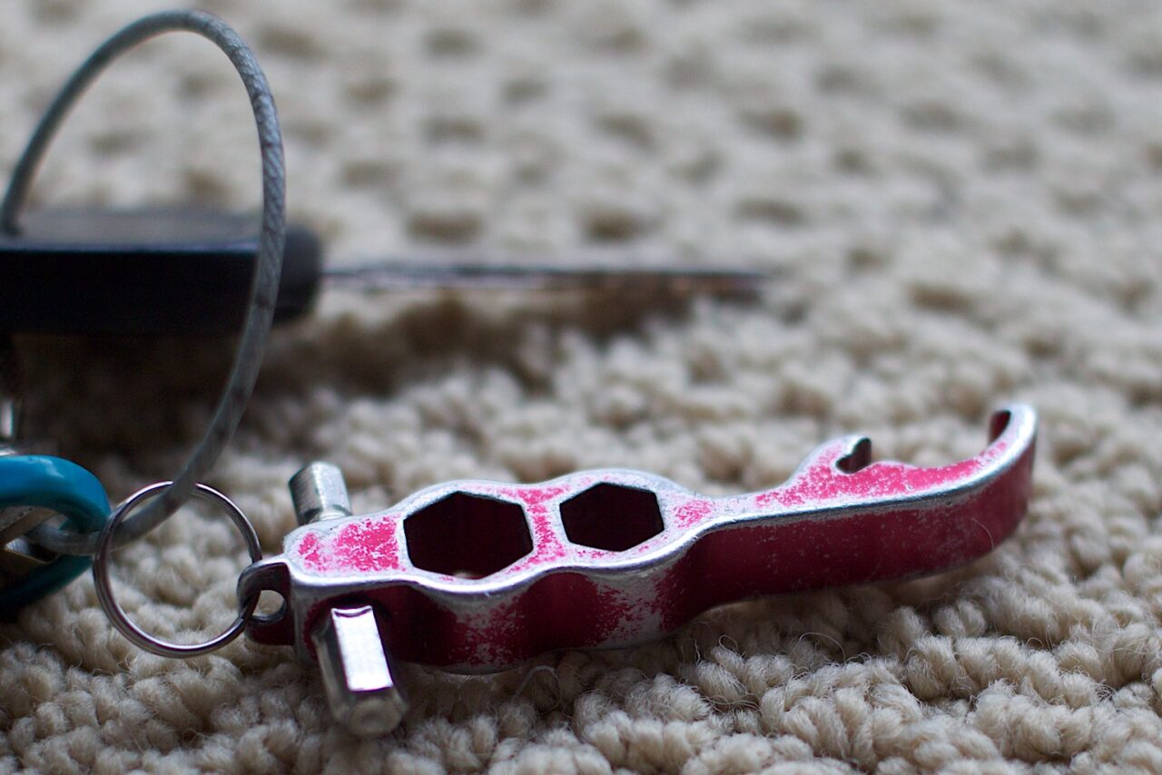 A well worn multi tool with Allen wrench probes, hex bolt and a bottle opener on a key chain.
