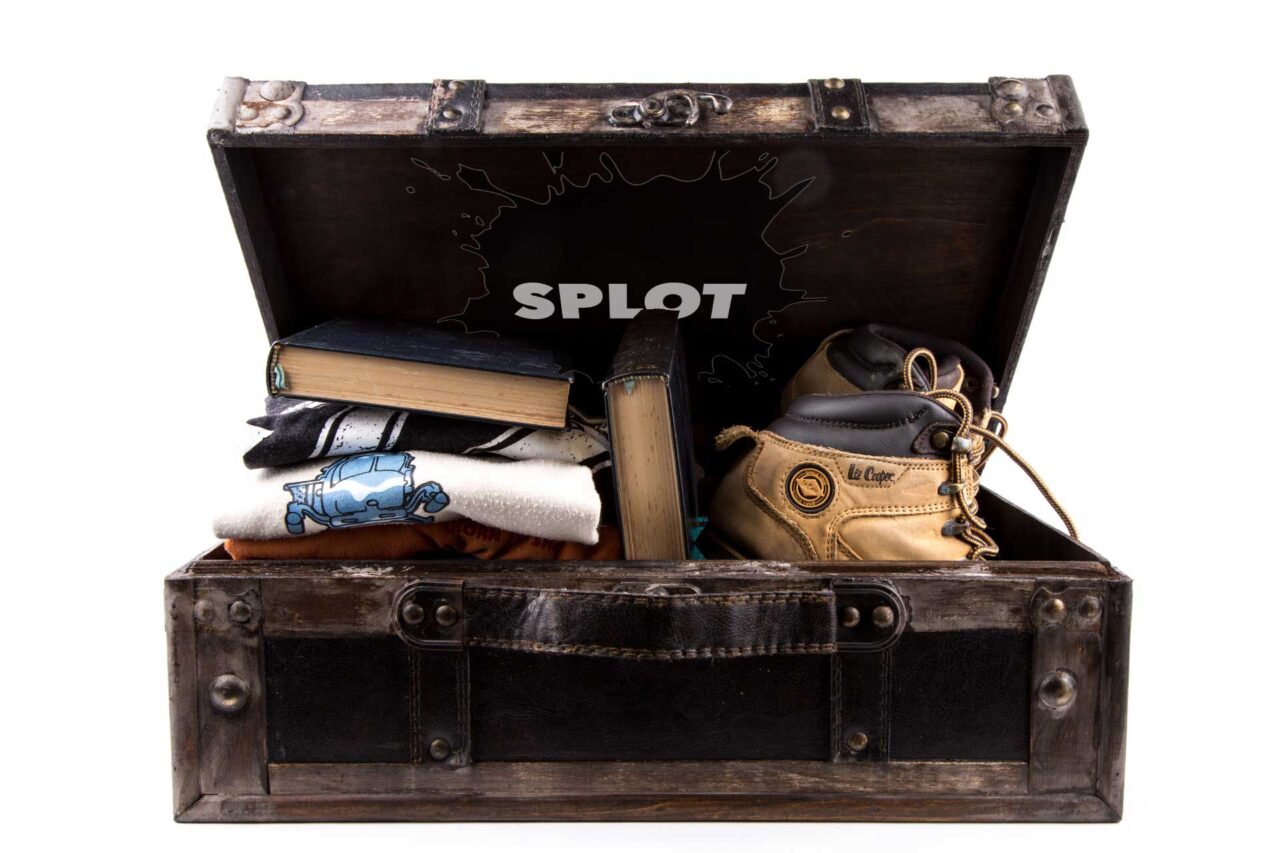 An open old footlocker full of shoes and clothes and books. A SPLOT logo is inserted on the top lid.