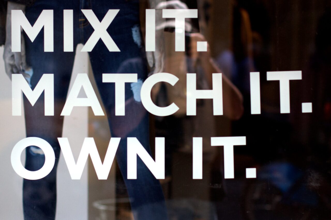 Large words on a daek window reading Mix it. Match it. Own It. very faintly in the window is the reflection of the photographer.