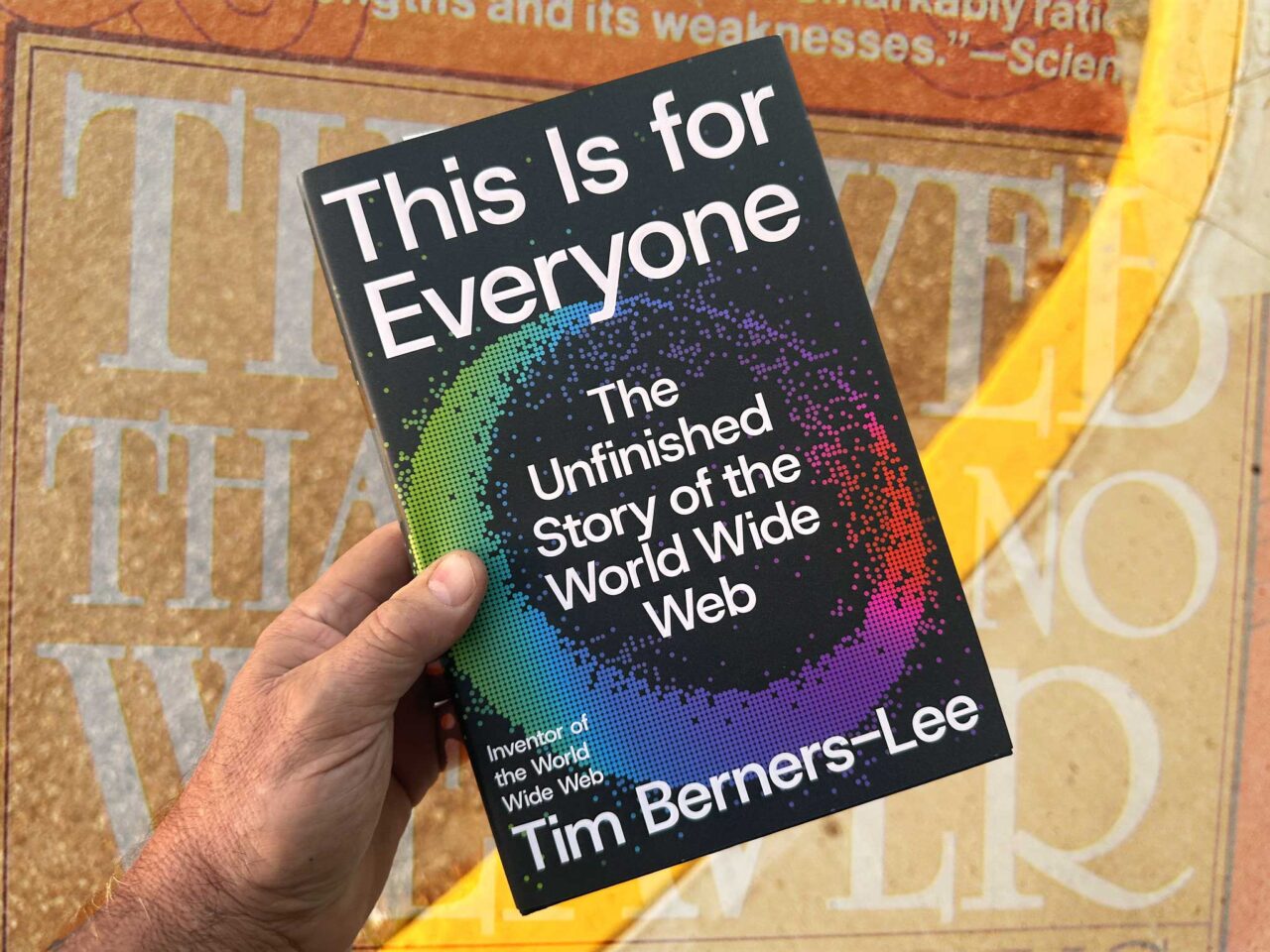 Hand in lower left corner holding the book This is for Everyone- the unfinished story of the world wide web by Tim Berners-Lee