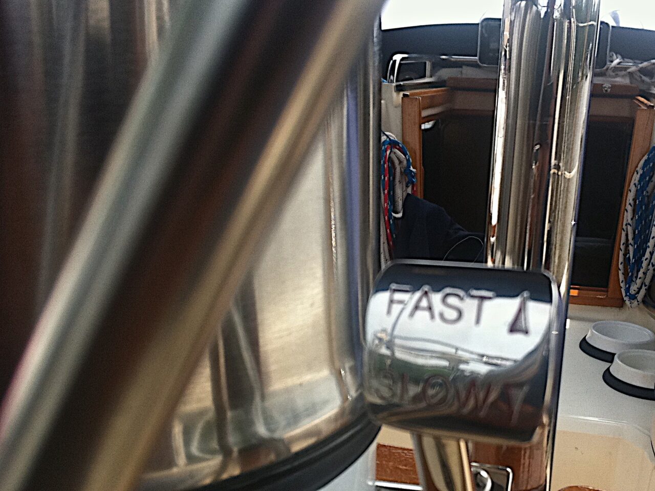 A speed throttle in a boat helm, chrome bar with arrows for fast and slow.