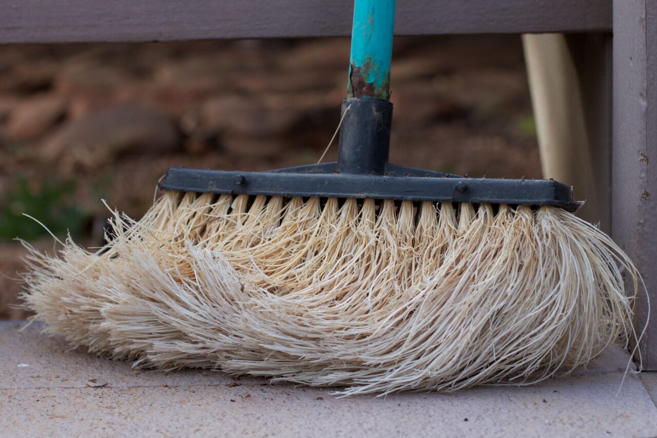 An old and worn mop handle broom.