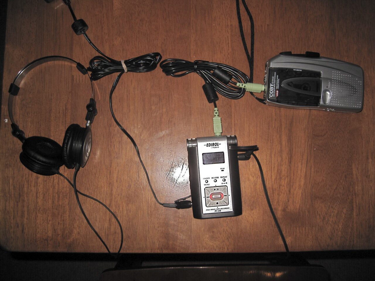 Really old audio cassette recorded connectedwith wires to a somewhat old mp3 audio recorder, with headphones on the side.