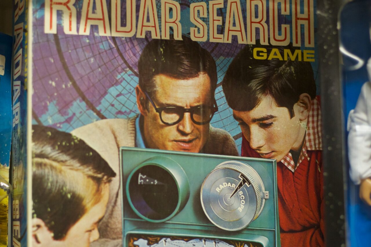 Vintage advertisement showing two young men examining a radar device beneath the words RADAR SEARCH GAME.