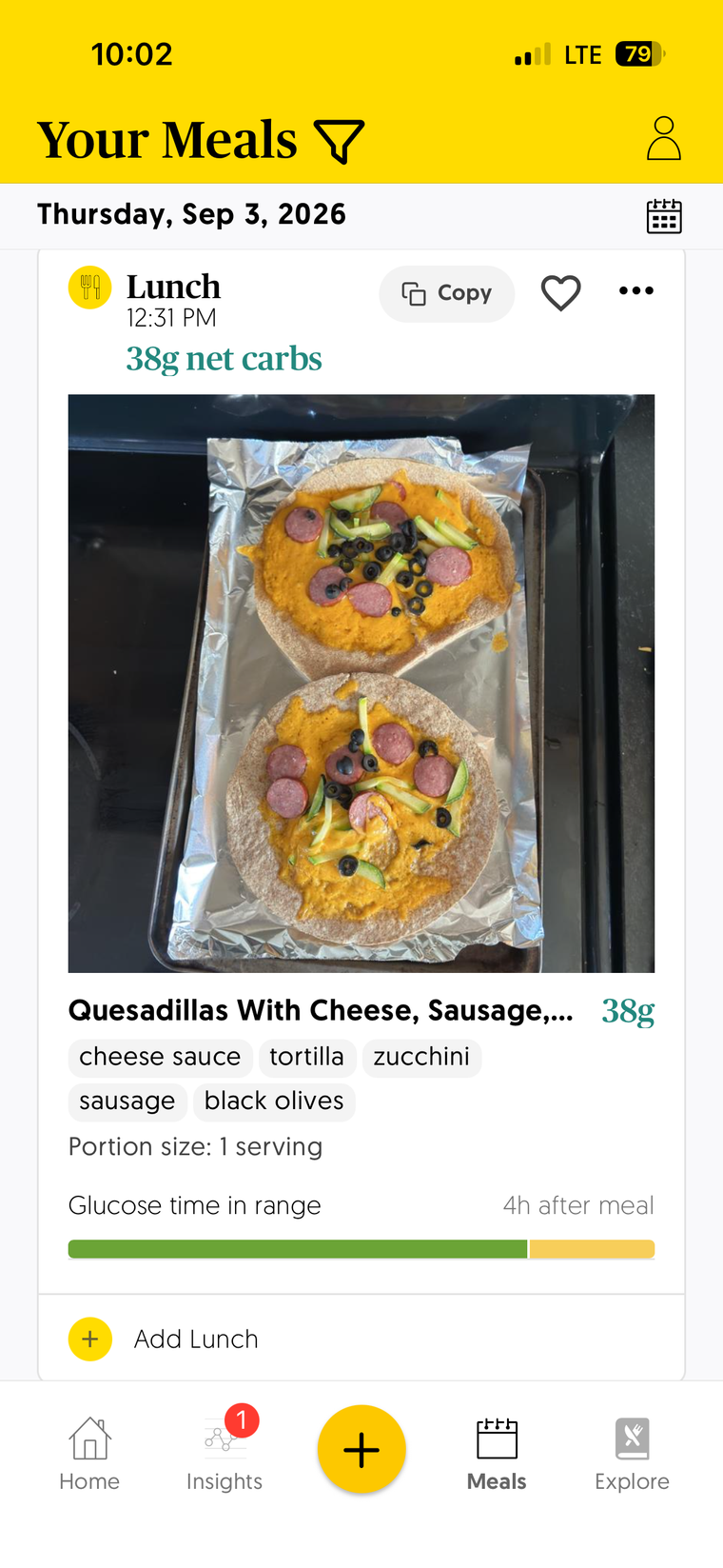 App screen identifying a lunch meal at 38g of carbs from a photo of melted cheese, sausage, and black olives on tw tortillas sitting on an oven pan)